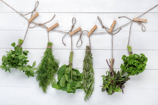 Bunches of different fresh herbs on white wooden background - Photo, image