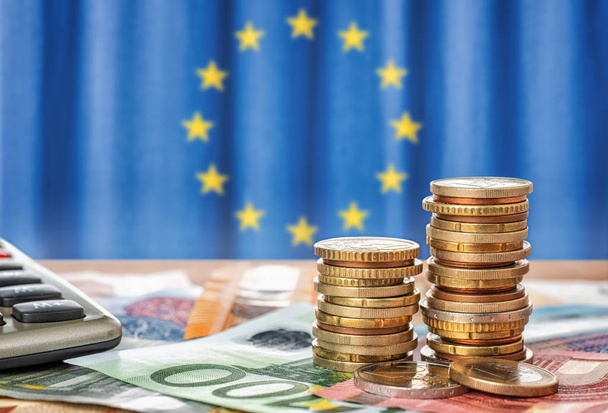 Banknoten und Münzen vor der Flagge der Europäischen Union - Foto, Bild