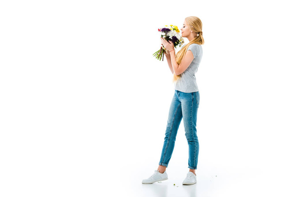 beautiful blonde girl smelling flowers and looking at them isolated on white - Photo, Image