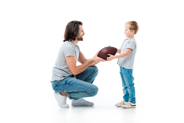 Caring padre dando palla da calcio americano a suo figlio isolato su bianco
 - Foto, immagini