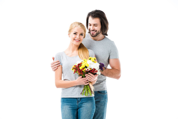Prachtige paar knuffelen terwijl vrouw met bloemen geïsoleerd op wit - Foto, afbeelding
