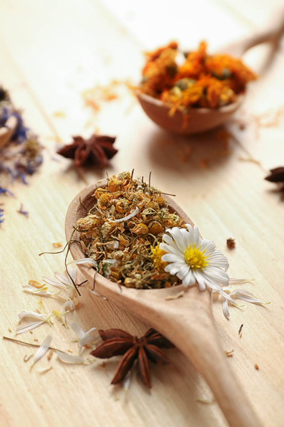 Wooden spoons with dried herbs and flowers on table - Photo, Image