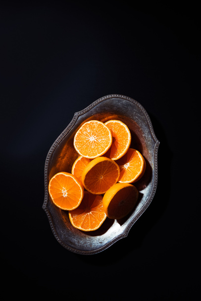 vista superior de las mitades de mandarinas cortadas en un tazón de metal sobre una mesa negra
 - Foto, Imagen