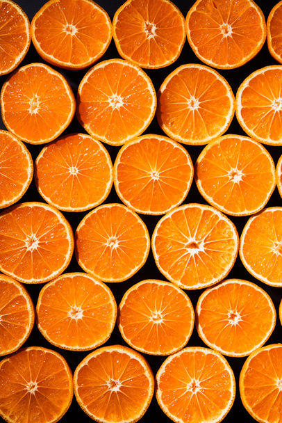 full frame of arranged cut tangerines halves on black background - 写真・画像