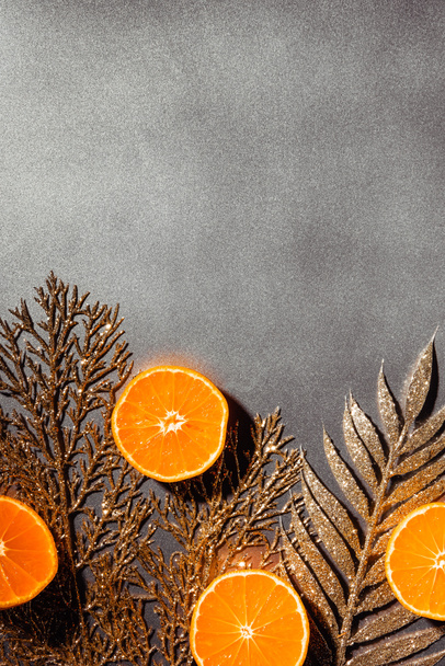 flat lay with fresh tangerines and decorative golden twigs on grey backdrop - Фото, изображение