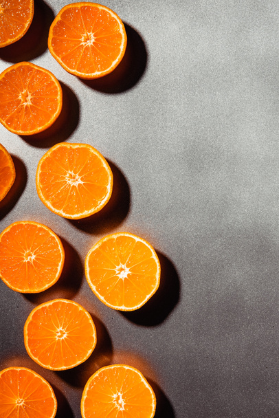 flache Lage mit angeordneten Mandarinenhälften auf grauem Hintergrund - Foto, Bild