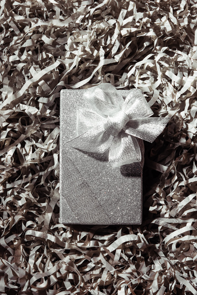 top view of silver christmas gift on grey paper confetti backdrop - Fotografie, Obrázek