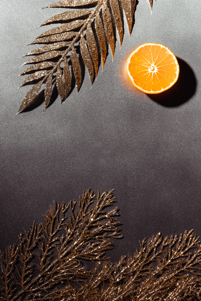 top view of cut tangerine half and decorative golden twigs on grey background - 写真・画像