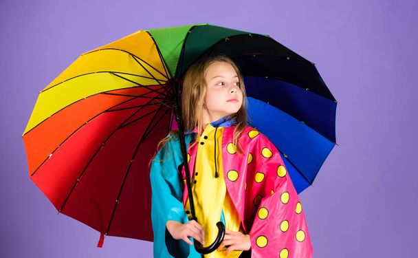 Kid girl happy hold colorful umbrella wear waterproof cloak. Waterproof accessories for children. Enjoy rainy weather with proper garments. Waterproof accessories make rainy day cheerful and pleasant - Fotografie, Obrázek