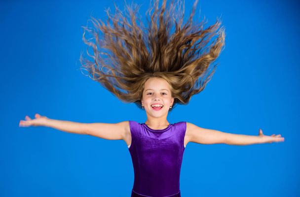Ballroom latin dance hairstyles. Kid girl with long hair wear dress on blue background. Hairstyle for dancer. How to make tidy hairstyle for kid. Things you need know about ballroom dance hairstyle - Foto, Imagem