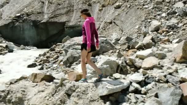 Turistické dívka jde po kamenech do horské řece - Záběry, video
