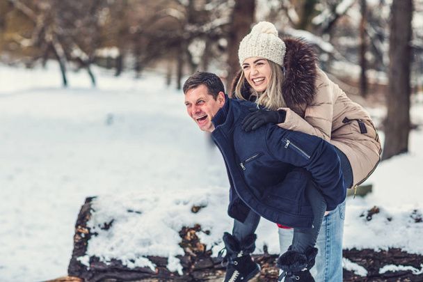 Семейное времяпровождение - влюбленная молодая пара в Зимнем парке веселится
 - Фото, изображение