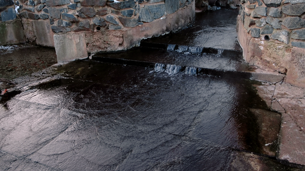 Wasser fließt aus der Leitung im Winterpark in den Teich. - Filmmaterial, Video