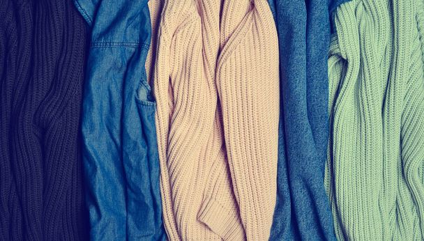 ニットのセーターやジーンズのクローズ アップのスタック。服の背景。女性のワードローブ. - 写真・画像