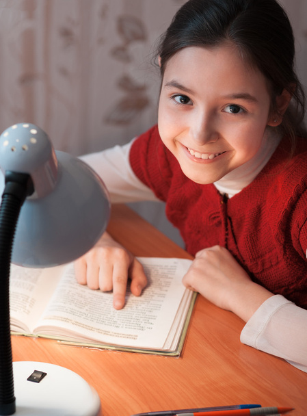 girl at desk reading a book by light of the lamp - Φωτογραφία, εικόνα
