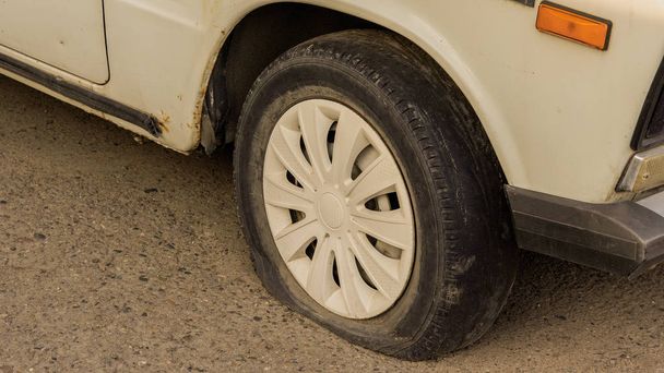 Neumático trasero plano en viejo coche oxidado
 - Foto, Imagen