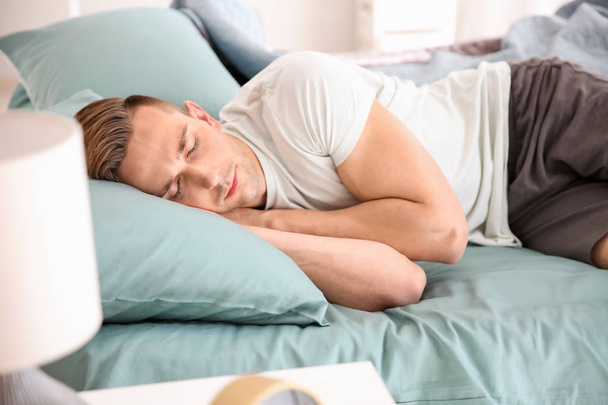 Hombre guapo durmiendo en la cama en casa
 - Foto, imagen