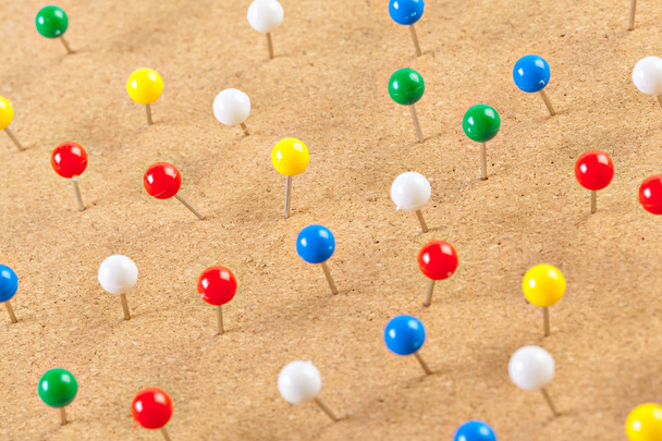 Close view of group of colorful thumbtacks pinned on corkboard - Foto, afbeelding