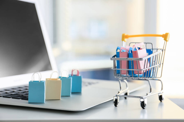 Kleine kar en laptop op tafel. Internet shopping concept - Foto, afbeelding