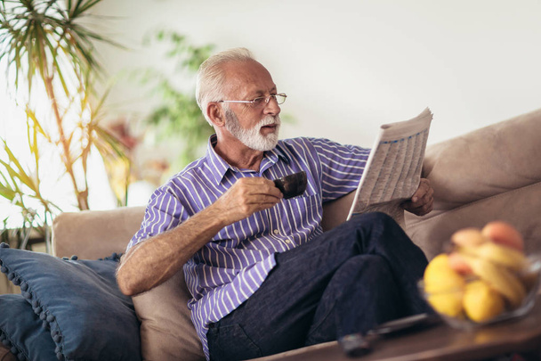 Senior man at home reading newspaper - Photo, Image