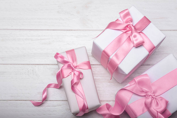 Scatole regalo con nastri rosa su sfondo bianco in legno
 - Foto, immagini