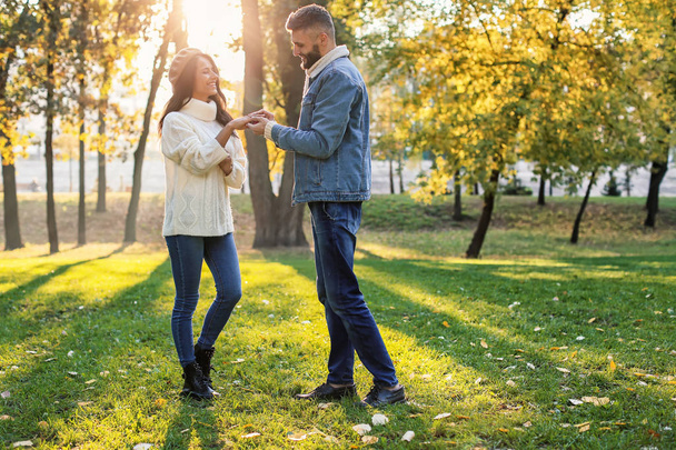 Jonge man brengen verlovingsring aan verloofde van vinger in herfst park - Foto, afbeelding