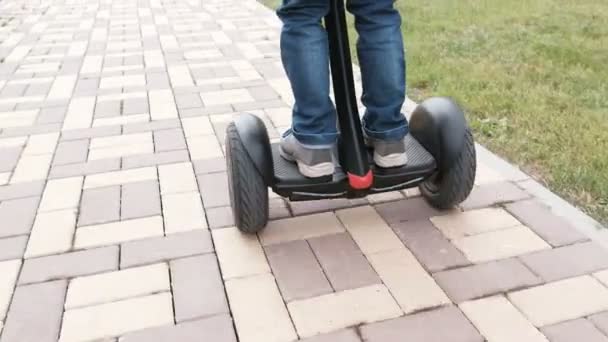 Unrecognizable boy is rolling on gyro scooter near the home. Back view. Legs close-up. - Video, Çekim