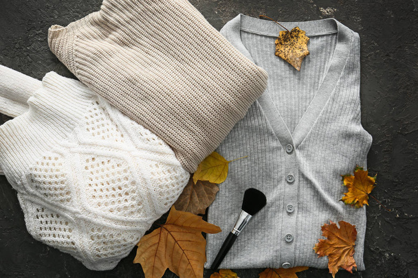 stylisches Outfit mit Schminkpinsel und Herbstblättern auf grauem Hintergrund, Draufsicht - Foto, Bild