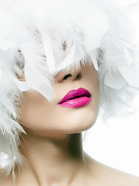 Retrato de Beautiful Girl en plumas blancas. mujer sexy joven con labios rosados, sombrero de pluma hermosa. Maquillaje de belleza
 - Foto, Imagen
