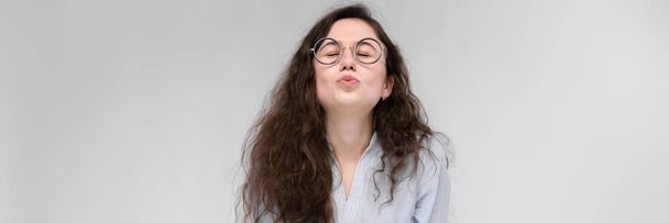 Young brunette girl with glasses. The girl pulls her lips for a kiss. The girl closed her eyes. - Photo, Image