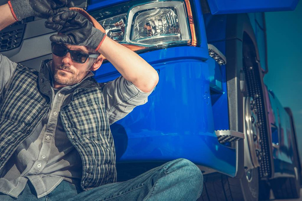 Müder kaukasischer Lastwagenfahrer in seinen 30ern, der sich vor seinem Sattelzug ausruht. Transportindustriekonzept. - Foto, Bild