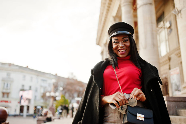African american fashion girl in coat and newsboy cap posed at street. - Foto, afbeelding