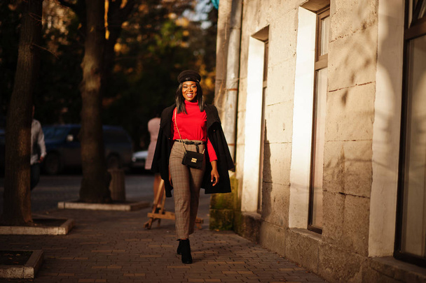 African american fashion girl in coat and newsboy cap posed at street. - Фото, зображення