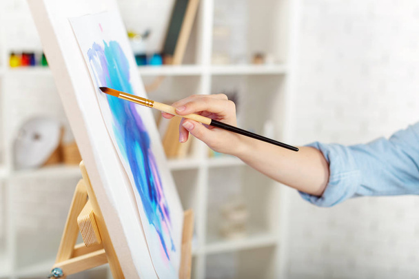 Young female artist painting picture in studio - Photo, image