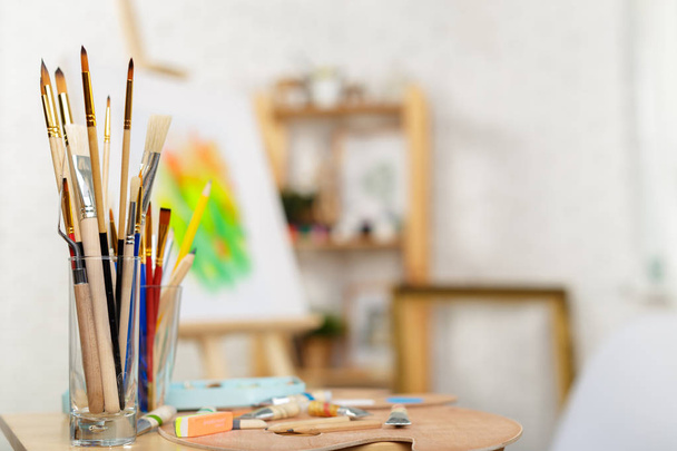 Painting supplies brushes and easel, workplace of artist.   - 写真・画像