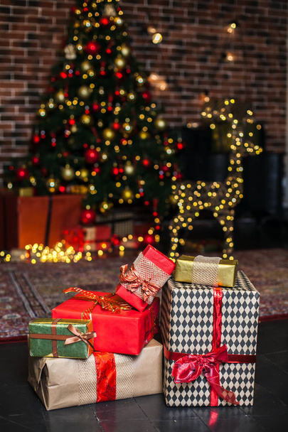 Close up Christmas gift box. Christmas presents in red and brown boxes on Christmas Tree background in loft interior copy space. - Φωτογραφία, εικόνα