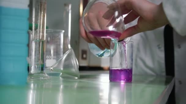 Chemical laboratory. Young woman making an experiment, liquid changing color - Materiaali, video
