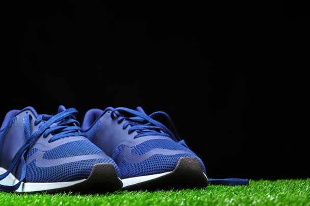 黒の背景に芝生の上のスポーツの靴のクローズ アップ  - 写真・画像