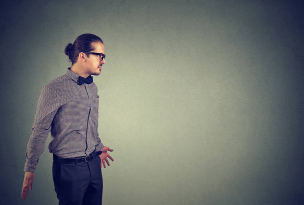 Frustrated man in glasses looking away with annoyed face expression on gray background - Photo, Image