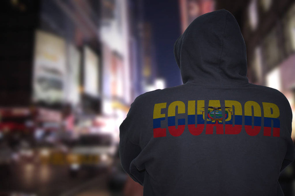 gevaarlijke man die op een straat in de nacht met zwarte hoodie stad met tekst ecuador op zijn rug - Foto, afbeelding