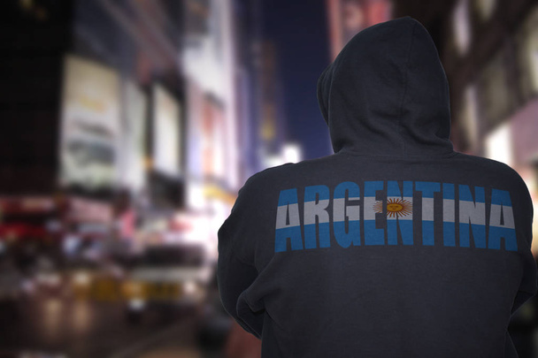 gevaarlijke man die op een straat in de nacht met zwarte hoodie stad met tekst Argentinië op zijn rug - Foto, afbeelding