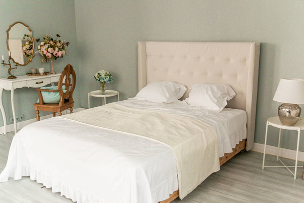Double bed with white linen, makeup table with a vase of flowers in the modern bedroom - Foto, immagini