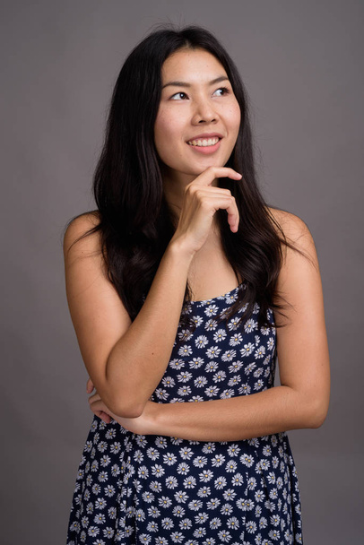 Азиатка в синем платье на сером фоне - Фото, изображение
