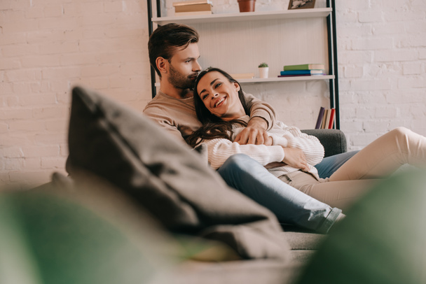 attractive young couple cuddling on couch at home - Fotoğraf, Görsel