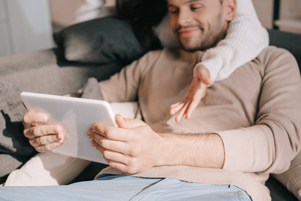 colpo ritagliato di giovane coppia utilizzando tablet insieme sul divano a casa
 - Foto, immagini