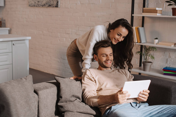 beautiful young couple using tablet together on couch at home - Photo, Image