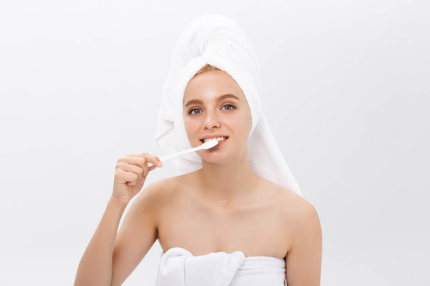 Красота портрет счастливой красивой полуобнаженной женщины, чистящей зубы зубной щеткой и смотрящей на камеру на белом фоне
. - Фото, изображение