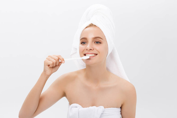 Schönheitsporträt einer glücklichen schönen halbnackten Frau, die sich mit einer Zahnbürste die Zähne putzt und isoliert vor weißem Hintergrund in die Kamera blickt. - Foto, Bild
