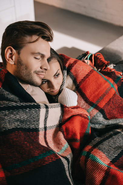 high angle view of happy young couple relaxing on couch and covering with plaid - Foto, immagini