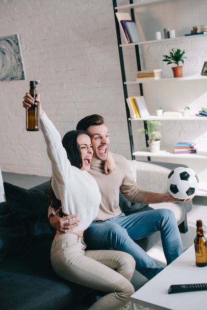 happy expressive young couple watching football game at home and cheering - Фото, зображення
